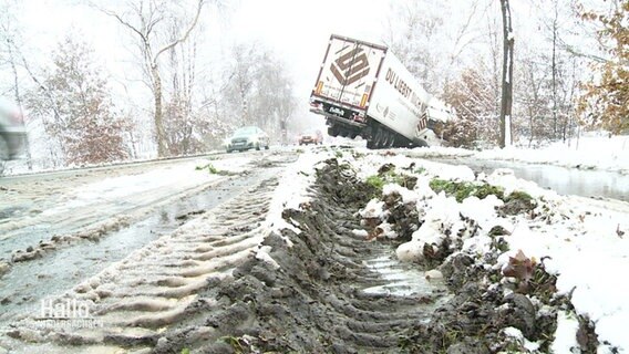 Ein Sattelzug ist von einer schneebedeckten Straße abgekommen und steckt im Graben. © Screenshot 