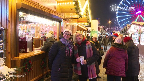 Mehrere Personen stehen mit einer Spendendose auf einem Weihnachtsmarkt. © Screenshot 