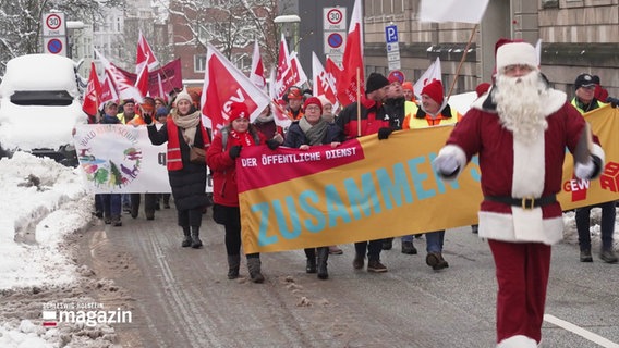 Ein Demonstrationszug des öffentlichen Dienstes, vorneweg marschiert ein als Nikolaus kostümierter Mensch. © Screenshot 