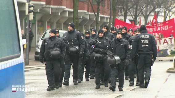 Eine Hundertschaft der Polizei geht vor einem Demonstrationszug. © Screenshot 