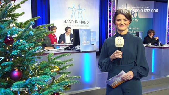 Moderatorin Frauke Rauner moderiert bei der Spendenaktion "Hand in Hand" im Funkhaus Schwerin. Links im Anschnitt ein Tannenbaum. © Screenshot 