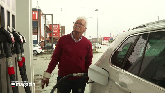 Ein älterer Mann beim Tanken seines Autos; er schaut kritisch auf die Anzeige der Zapfsäule. © Screenshot 