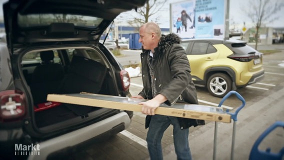 Ein Mann lädt längliche Ikea-Ware in den Kofferraum eines Autos © Screenshot 