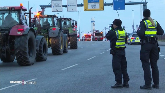 Polizisten sehen auf einer Autobahn stehend den abrückenden Bauern in ihren Trekkern zu. © Screenshot 