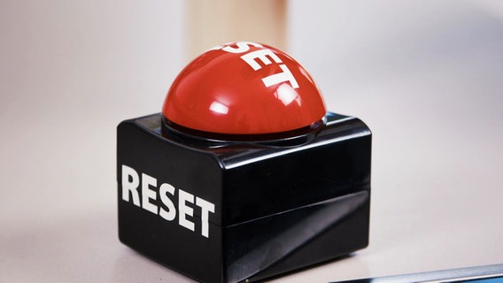 Ein schwarzer Buzzer mit rotem Knopf zum Drücken, auf dem in Großbuchstaben "Reset" steht. © Screenshot 