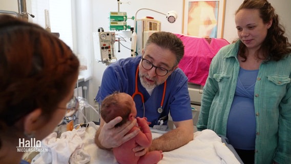 Ein Doktor mit einem Neugeborenen in der Hand. © Screenshot 