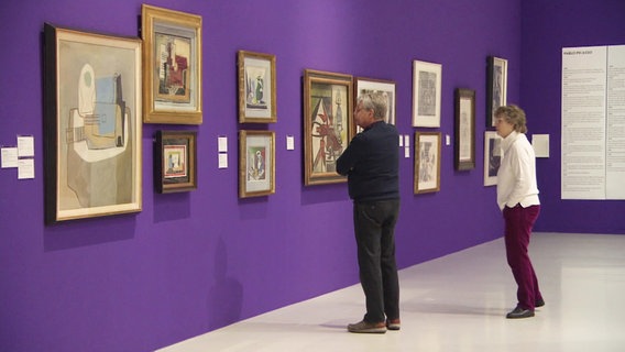 Besucher im Sprengel Museum vor einer lilanen Wand mit Gemälden. © Screenshot 