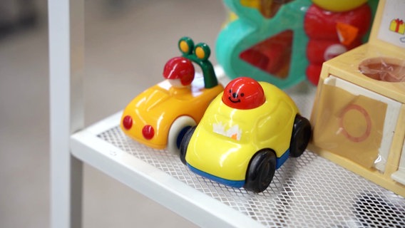 Zwei Spielzeugautos stehen in einem Regal. © Screenshot 