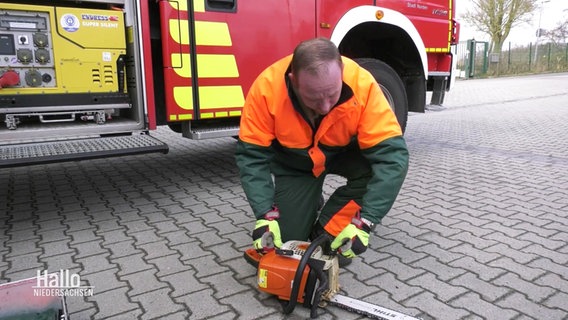 Ein Feuerwehrmann testet eine Kettensäge. © Screenshot 