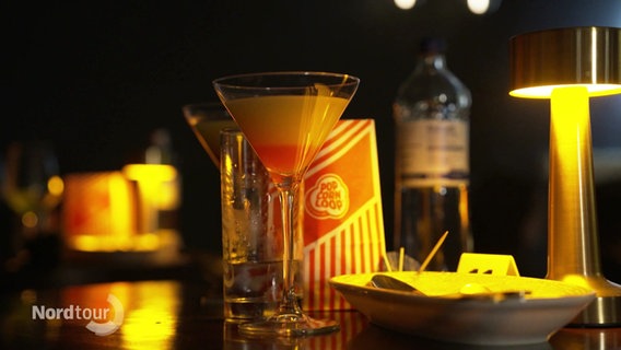 Kino-Menü in schummrigen Licht: Popcorn, ein Drink im Martiniglas, Wasser und Spaghetti. © Screenshot 
