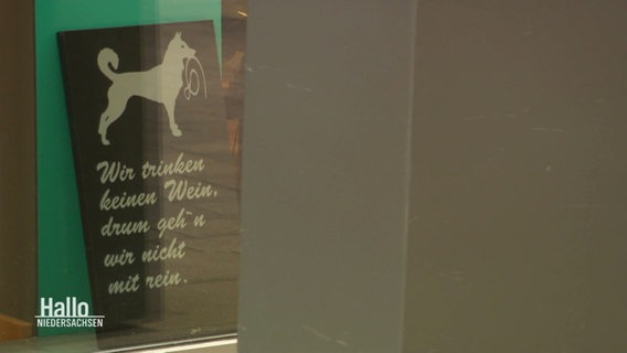 Ein Schild mit der Grafik eines Hundes und der Aufschrift: Wir trinken keinen Wein, drum gehn wir nicht mir rein. © Screenshot 