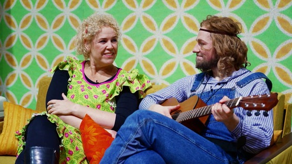Frederike Witthuhn und ein Mann mit Gitarre sitzen auf einem Sofa. © Screenshot 