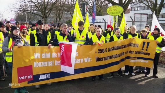 Streikende in gelben Westen tragen ein Banner vor sich her. © Screenshot 