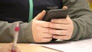 Ein Jugendlicher hält sein Smartphone in den Händen. © Screenshot 