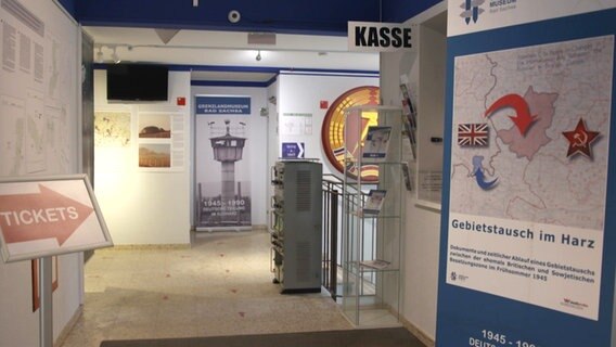 Ein Blick in den Eingangsbereich des Grenzlandmuseums Bad Sachsa mit Kasse, verschiedenen Plakaten und Objekten. © Screenshot 