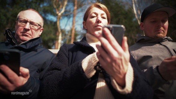 Drei Menschen stehen nebeneinander und schauen auf ihre Handys. © Screenshot 