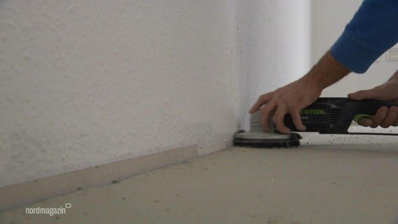 Jemand bearbeitet mit einem Handschleifgerät den Fußboden. © Screenshot 