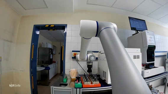Ein Roboterarm greift eine Probe. © Screenshot 