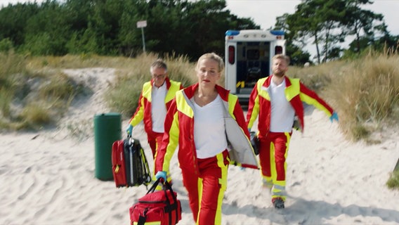Tanja Wedhorn eilt in ihrer Rolle als Notärztin über einen Sandstrand. © Screenshot 