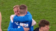 Zwei Spieler des Vereins Hansa Rostock umarmen sich. © Screenshot 