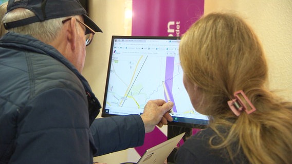 Zwei Menschen betrachten an einem Bildschirm den Verlauf der geplanten Energietrasse vom Amplion © Screenshot 