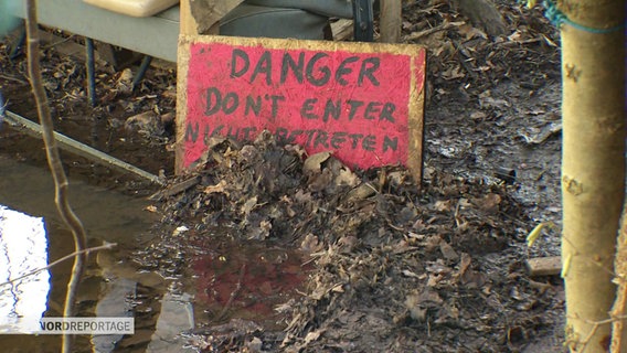 Auf dem blätterbedeckten Boden steht ein Hilzschild mit der Aufschrift DANGER - don't enter - nicht betreten. © Screenshot 