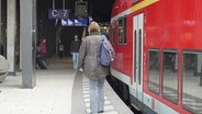 Eine Pendlerin neben einem Zug auf dem Bahnsteig. © Screenshot 