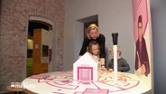 Zwei Kinder und eine Frau beschäftigen sich mit der interaktiven Ausstellung des Hansemuseums in Lübeck zum Thema "Navigation". © Screenshot 