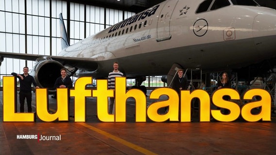 Große Leuchtbuchstaben, mit denen "Lufthansa" geschrieben steht, in einem Hangar. © Screenshot 