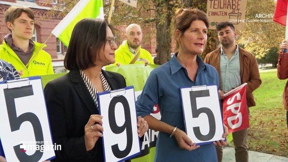 Mehrere Frauen halten Schilder mit Zahlen hoch. © Screenshot 