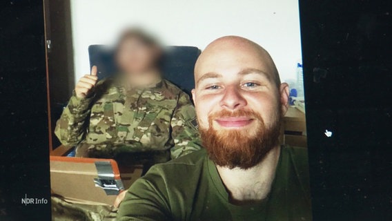 Aufnahme von "Eugen" als er noch für die Ukraine an der Front war. Ein Mann mit Glatze und einem vollen, rötlichen Bart. © Screenshot 