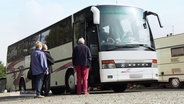 Senioren stehen vor einem Reisebus.  