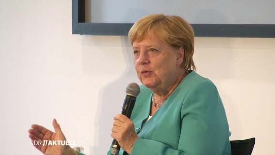 Kanzlerin Merkel sitzt auf einer Bühne.  