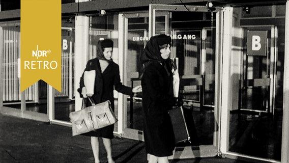 Stewardessen in Dienstkleidung vor Flughafengebäude  