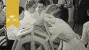 Mädchen zieht Lose aus einer hölzernen Trommel (1958)  