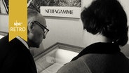 Besucher an einer Vitrine in einer Ausstellung übder das KZ Neuengamme (1965)  