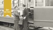 Schichtwechsel bei der Straßenbahn: Ein Fahrer in alter Uniform schüttelt einem Fahrer in neuer Uniform die Hand (1960)  