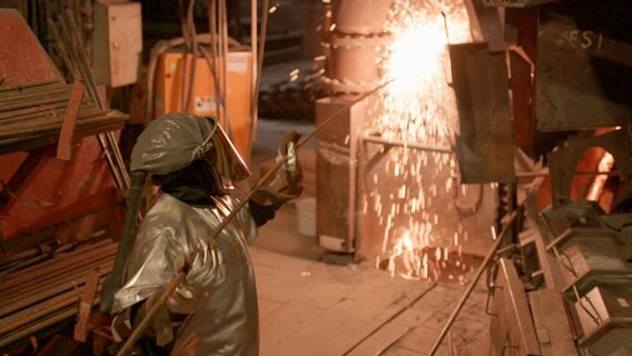 Arbeiter in hitzebeständiger Schutzkleidung in einem Kupferwerk vor dem Schmerzofen. Die Funken sprühen. © NDR/HTTV Produktion/Michael Höft 