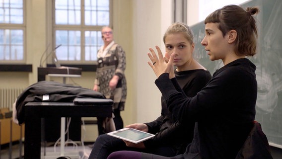 Zwei Frauen in einem Hörsaal. Eine von ihnen gebärdet. © NDR/Lisa Wolff/Henning Wirtz 