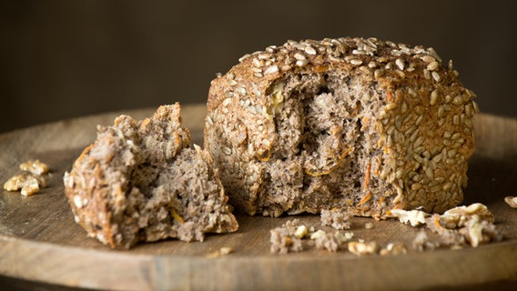 Ein aufgerissenes Brot mit Möhren mit Walnüssen im Teig liegt auf einem Teller. © Braaker Mühle 