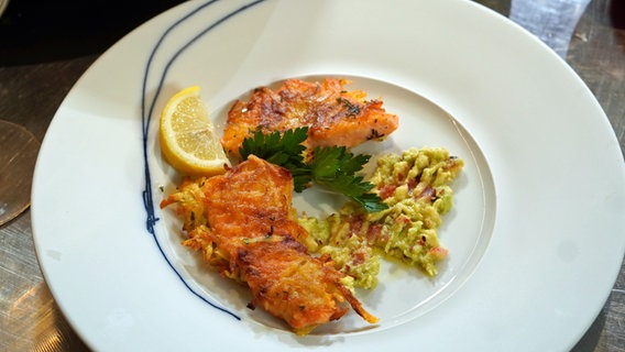 Lachsforelle in Kartoffel-Senf-Panade mit Avocado-Dip auf einem weißen Teller serviert. © NDR Foto: Florian Kruck