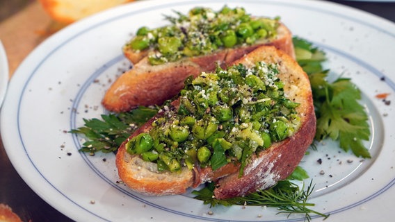 Crostini mit Spargel-Erbsen-Creme  auf einem Teller angerichtet. © NDR Foto: Florian Kruck