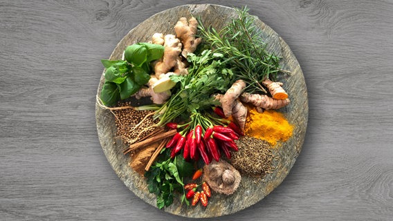 Ein schön angerichteter Teller mit Kurkuma, Chili, Ingwer und verschiedenen weiteren Gewürzen steht auf einer Holzplatte. Ein schön angerichteter Teller mit Kurkuma, Chili, Ingwer und verschiedenen weiteren Gewürzen steht auf einer Holzplatte. © NDR