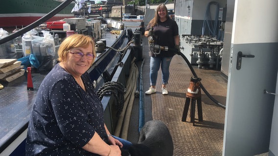 Andrea Herforth (vorne) leitet die Schiffstankstelle zwischen Landungsbrücken und der Elbphilharmonie. Seit 16 Jahren betankt sie Schuten, die HPA-Flotte oder die Barkassen der Wasserschutzpolizei. Der Umgangston ist rau auf dem schwimmenden Ponton. Zusammen mit Birgitt von Zengen betankt sie ab 7.00 Uhr jeden Wochentag bis zu 20 Schiffe. © NDR/Miramedia GmbH/Stefan Weiße 