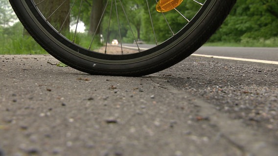 Ein Fahrradreifen steht an einer Fahrbahnmarkierung. © NDR Foto: Screenshot