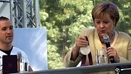 Angela Merkel betrachtet eine Medaille © Screenshot 
