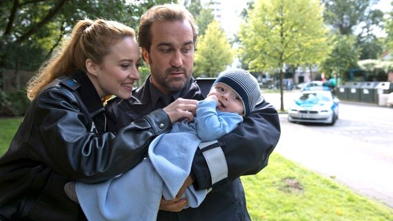 Nina Sieveking (Wanda Perdelwitz, l.) und Paul Dänning (Jens Münchow, r.) sind ganz vernarrt in Baby Pauli. Sie sollen es zu seiner Mutter zurückbringen. © NDR/Thorsten Jander 