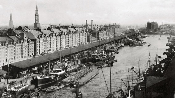 Sandtorhafen, etwa 1889: Seeschiffe liegen umringt von kleineren Schuten an der Kaimauer, dahinter die gerade errichtete Speicherstadt. © Hamburger Hafen und Logistik AG 
