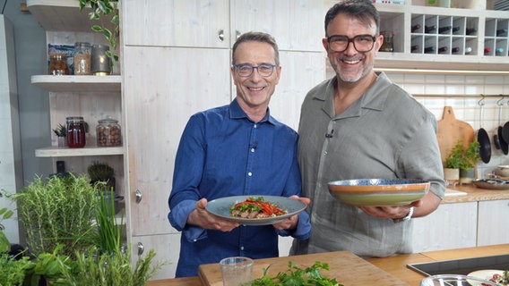 Tarik Rose und Ernährungs-Doc Matthias Riedl halten Teller mit Gemüsesalat in die Kamera. © NDR Foto: Florian Kruck