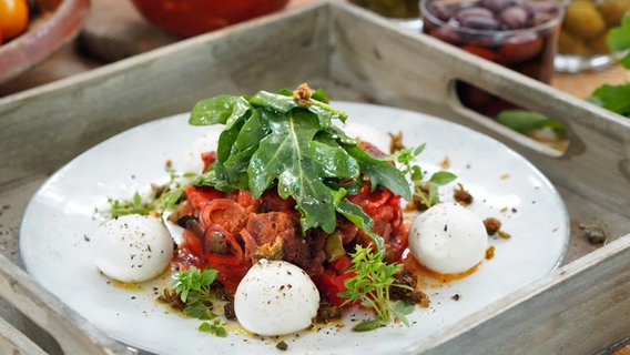 Dinkelbrot-Salat mit Mozzarella und Kapern auf einem Teller angerichtet. © NDR Foto: Florian Kruck